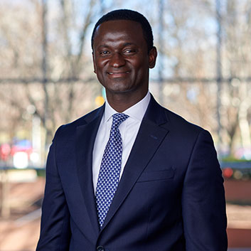 Momodou Bojang smiling in a navy suit